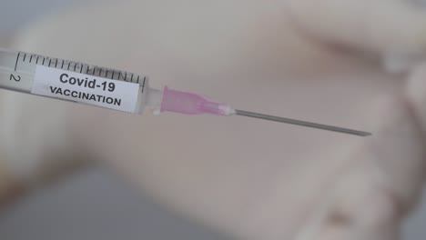 Shot-Of-Covid-19-Vaccination---Hand-Removes-Cap-Of-Syringe-Needle---close-up