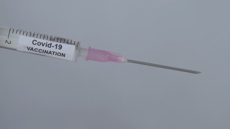 Syringe-With-Covid-19-Vaccine-Fluid-Drops-On-Needle-Flick-By-Finger,-Close-Up-Shot
