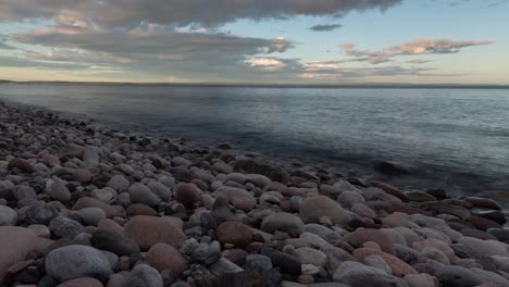 Time-lapse-footage-of-rocky-beach-at-sunset-and-rainbow-in-a-far