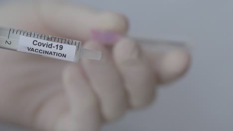 Attaching-Needle-To-Syringe-With-Covid-19-Vaccination-Label---close-up
