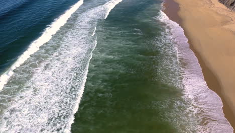 Aerial-drone-view-of-ocean-with-waves-crashing-and-sand-shot-in-4k-high-resolution