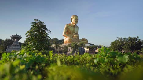 Panorámica-De-4k-Sobre-La-Hierba-Hacia-La-Estatua-Del-Monje-Dorado-Luang-Pu-Thuat