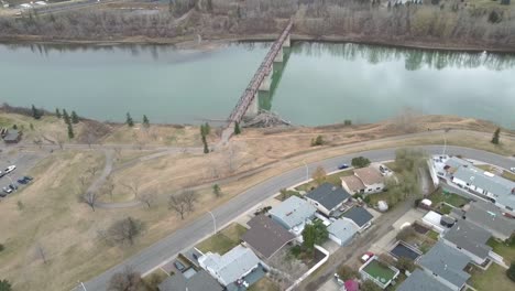 aerial-birds-eye-view-pan-over-poluted-North-Saskatchewan-river-at-Rundel-Park-past-an-empty-quiet-pedesterian-bridge-by-park-homes-during-COVID-19-restriction-where-social-distancing-is-practiced