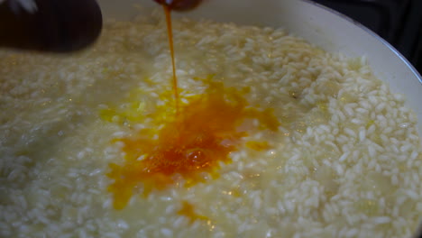 Italian-Chef-pouring-a-yellow-saffron-mixture-with-pistils-into-risotto-milanese