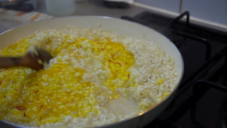 Italian-Chef-cooking-yellow-saffron-risotto,-stirring-the-saffron-in-the-creamy-rice