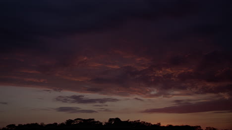 Atemberaubender-Zeitraffer-Eines-Magischen-Sonnenaufgangs-Mit-Goldenen-Farben,-Die-Die-Vorbeiziehenden-Wolken-über-Einem-Wald-Erhellen