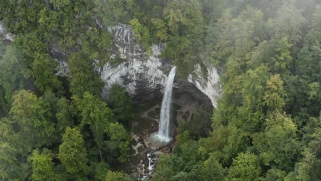 Misty-Wildenstein-Waterfall-in-the-southern-Austrian-Alps,-Aerial-dolly-in-lowering-approach