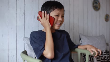 Retrato-De-Niño-Asiático-Hablando-Y-Sonriendo-Al-Teléfono
