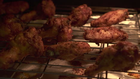 Pan-left-of-chicken-wings-while-roasting-in-a-hot-oven,-grilled-to-perfection