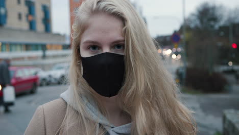Blonde-woman-with-black-face-mask-holding-a-package,-zoom-in,-slow-motion
