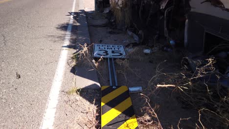 tilt-up-from-a-downed-speed-limit-sign-along-with-an-illegally-dumped-burned-trailer-and-trash-to-the-roadway,-Scottsdale,-Arizona