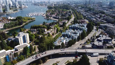 aerial-hold-dolly-roll-over-false-creek-granville-island-waterfront-residential-condominium-apartment-townhouse-homes-parked-yachts-sail-boats-parks-forests-luxury-towers-modern-architecture-bridges