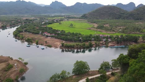 Drone-shot-moving-past-mountain-to-river-and-rice-patties-in-Phong-Nha