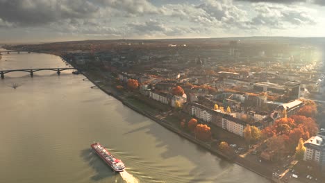 Revealing-Shot-in-golden-light-aerial-shot-of-Mainz-in-Germany-by-a-Drone-with-the-Dome-in-the-back-showing-the-city-of-Biontech-in-front-of-the-Rhine-river
