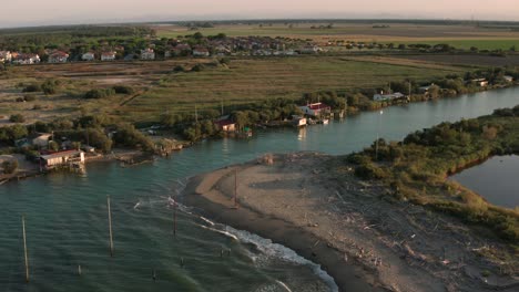 Aerial-shot-of-the-valleys-near-Ravenna-where-the-river-flows-into-the-sea-with-the-typical-fishermen's-huts