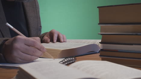 Mann-Studiert-Mit-Büchern-Und-Notizblock-Auf-Dem-Schreibtisch,-Grüner-Bildschirmhintergrund-4k