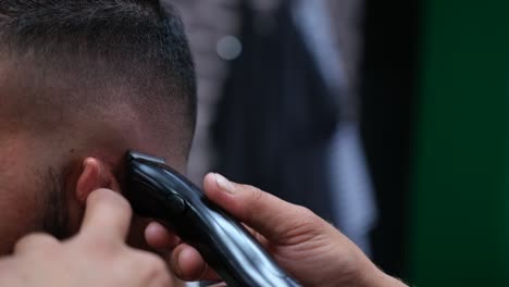 Close-up-of-a-barber-using-an-electric-razor-to-give-a-male-customer-a-very-short-cut
