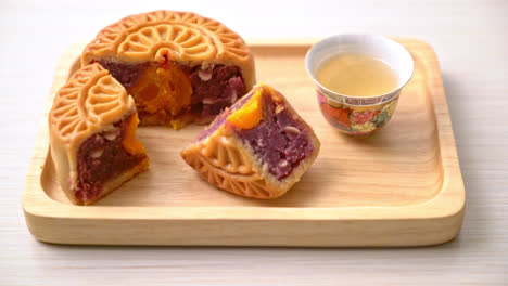Chinesischer-Mondkuchen-Lila-Süßkartoffel--Und-Eigelbgeschmack-Mit-Tee-Auf-Holzplatte