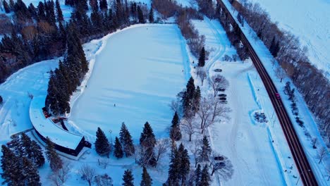2-8-Edm-Victoria-Park-Luftdrohne-Halten-über-Künstliche-Pandemiebeschränkung-Sonnenuntergang-Winter-Schneebedeckte-Hauptstadt-Edmonton-Größte-Outdoor-skating-arena-In-Alberta-Mit-Nur-4-Personen,-Die-Herumrutschen