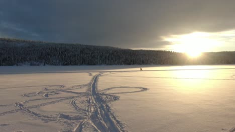 Schöne-Winterlandschaft-Mit-Skifahrern-Auf-Einem-Zugefrorenen-See-Mit-Sonnenuntergang-Und-Bergen-Im-Hintergrund