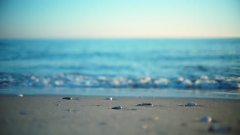 Sand-and-pebbles-at-the-beach-with-defocused-ocean-waves-behind-it