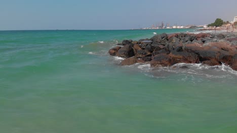 Eine-Filmische-Drohnenansicht-Der-Arabischen-Küste,-Meereswellen-Aus-Der-Vogelperspektive,-Die-Gegen-Die-Leeren-Felsen-Schlagen,-Vereinigte-Arabische-Emirate,-4K-Aufnahmen