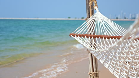 Empty-hammock-on-beach-and-coast-in-background