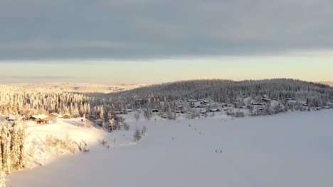 Luftaufnahme-Des-Winterresorts-Mit-Zugefrorenem-See-Und-Skifahrern-In-Norwegen