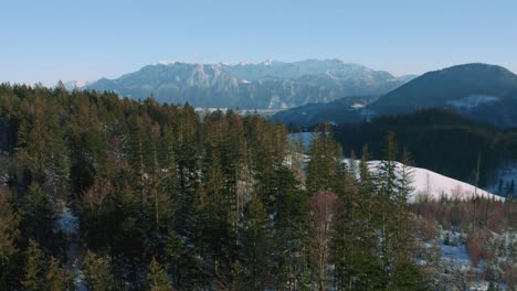 4K-Luftdrohnenflug-über-Schneebedeckten-Hügeln-Und-Grünen-Waldbaumwipfeln-In-Den-Bayerischen-Alpen-Im-Winter-In-Deutschland,-In-Der-Nähe-Von-Österreich