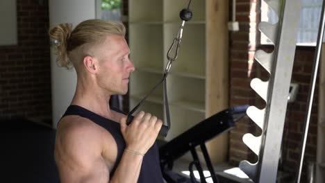 Tattoo-man-muscles-in-home-gym-doing-single-arm-lat-pulldown-shot-from-side