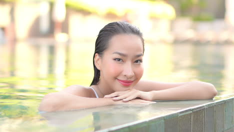 Verführerische-Asiatische-Frau-Im-Pool-Lächelt-Und-Schaut-In-Richtung-Rahmen