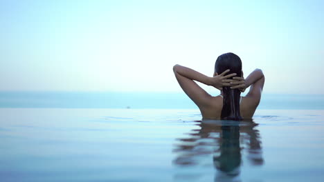 Young-woman-emerges-from-infinity-pool.-Slow-motion