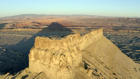 Drone-footage-flying-over-Factory-butte-with-crazy-rock-formations-and-textures-at-golden-hour-in-Utah,-moonscape-landscape