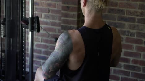 Tattoo-man-muscles-in-home-gym-doing-close-grip-lat-row-shot-from-behind