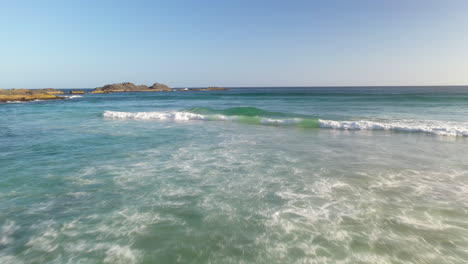 Waves-breaking-over-rocky-Australian-beach-coastline,-aerial-tracking-view