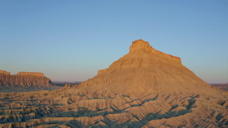Drone-aerial-footage-of-Factory-Butte-at-golden-hour-sunrise,-sunset-with-beautiful-rock-formations-in-Utah