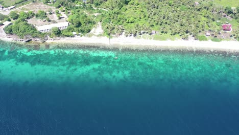 Aerial-top-down-shot-of-deep-blue-ocean-and-turquoise-transparent-shore-during-sunny-day-on-the-Philippines