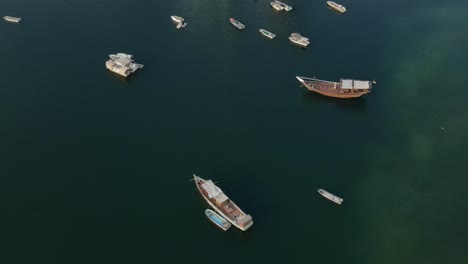 Vista-Superior-De-Drones-De-Los-Tradicionales-Barcos-De-Pesca-árabes-Amarrados-En-La-Superficie-Del-Mar-Del-Golfo,-Paisaje-Marino-Con-Vistas-De-Barcos-Desde-Arriba