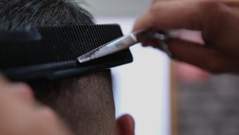 Extreme-close-up-as-a-barber-finishes-up-blending-a-fade-on-a-male-customer's-haircut