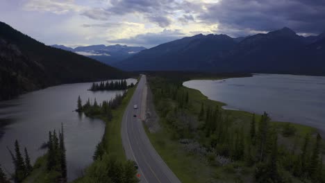 Twilight-summer-aerial-panout-drop-over-highway-humpjack-road-within-mountain-valley-dividing-lakes-marshes-some-clear-skies-partial-clouds-with-RV-travellers-at-birds-eye-view-lush-green-beaches-2-2