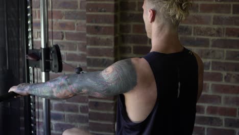 Tattoo-man-muscles-in-home-gym-doing-lat-rows