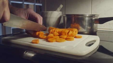 Picar-Zanahorias-En-La-Tabla-De-Cortar-Con-Un-Cuchillo-En-La-Cocina,-Primer-Plano