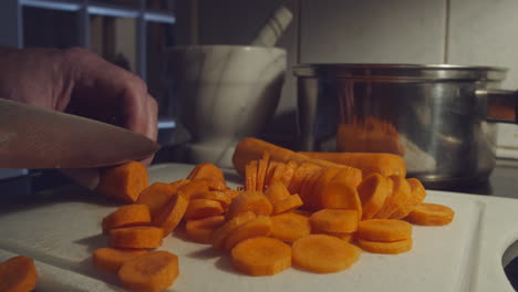 Chopping-pile-of-carrots-in-kitchen-on-cutting-board