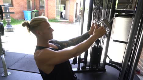 Tattoo-man-muscles-in-home-gym-doing-incline-cable-lat-row