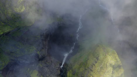 Top-down-aerial-drone-shot-of-deep-Mulagljufur-canyon-Wirth-misty,-foggy-cloud,-and-green-moss-in-Southern-Region-in-Iceland