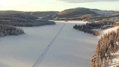 Höhenluftaufnahme-Von-Skifahrern-Auf-Zugefrorenem-See-Und-Bergen-Im-Hintergrund