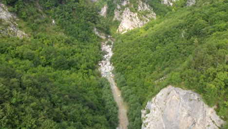 Drone-flying-above-wild-river-running-through-forest-canyon-in-Slovenia,-tilt