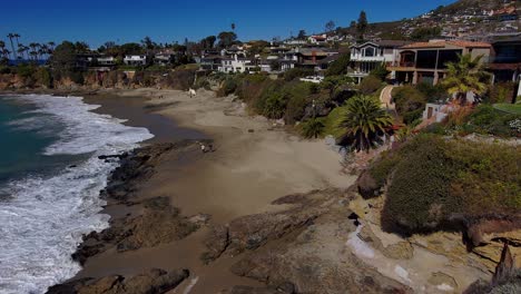 Aerial-view-of-a-couple-walking-along-a-beach-in-Laguna-Beach,-California