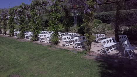 Rows-Of-White-Folding-Chairs-On-The-Lawn-Before-The-Arrival-Of-Guests---drone,-wideshot