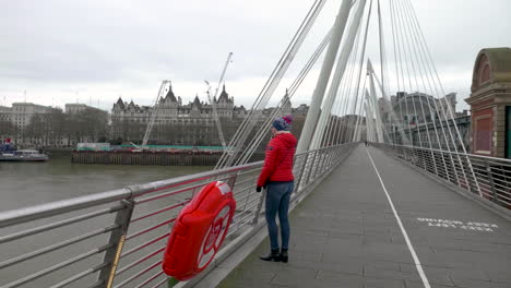 Slow-motion-shot-of-young-woman-and-the-view-she-has-from-the-Golden-Jubilee-Bridge,-London
